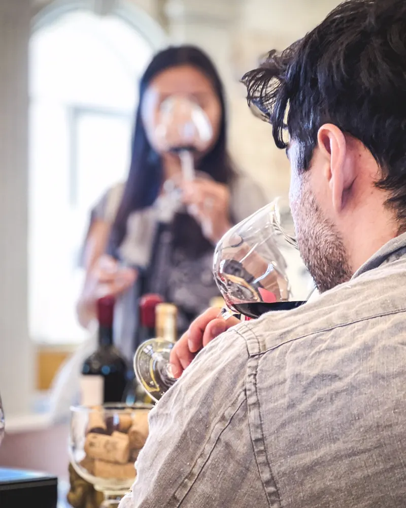 A guest smelling a glass of red wine at a winery tasting