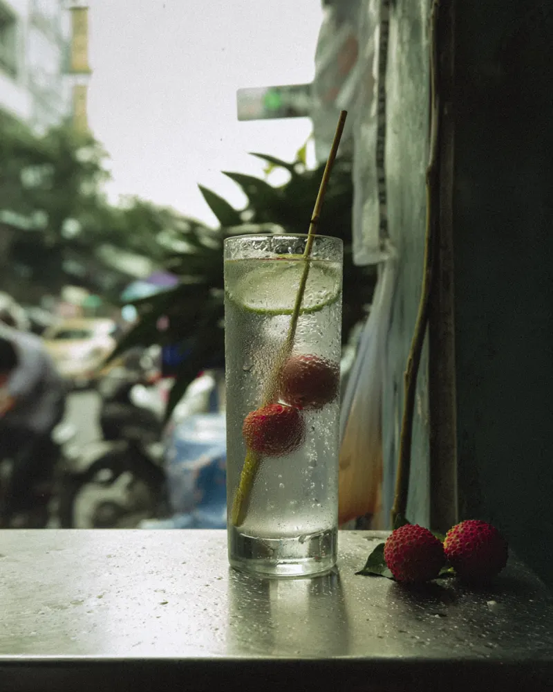 Lychee Collins in a tall highball glass with soda, lime and fresh lychees