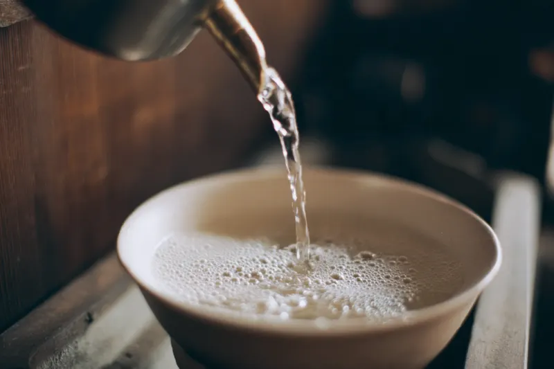 Bubbles forming on fresh baijiu as it flows into a white bowl