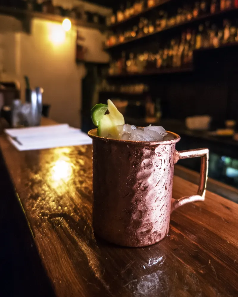 Silk Road Mule in a copper mug with crushed ice, lime and fresh ginger on a bar counter