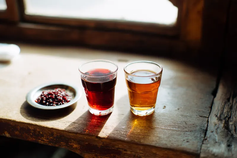 Young red and aged amber red-yeast rice wine side by side, with red yeast rice