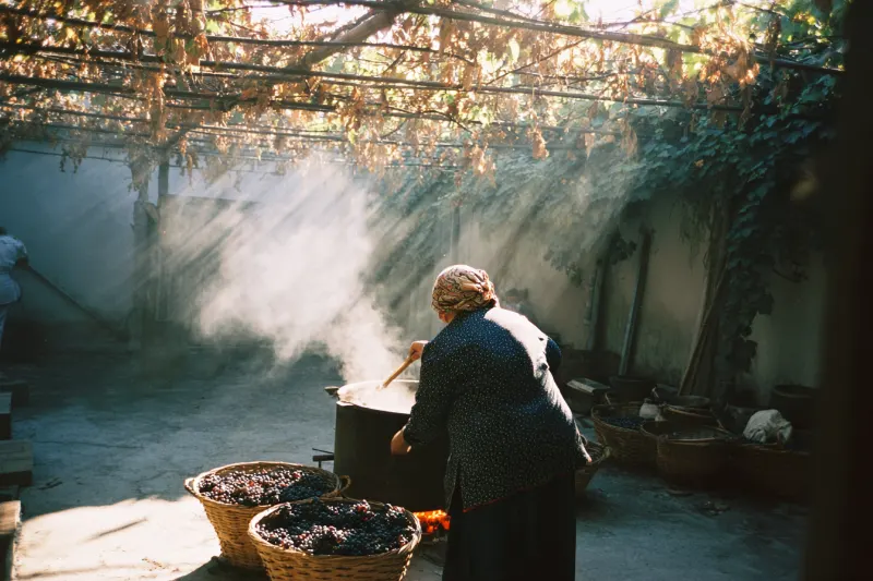 Grape juice boiling over a wood fire for musallas in a courtyard in Awati, Xinjiang