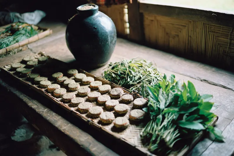 Herbal wine starter cakes drying on a bamboo tray in a Shui village, Guizhou
