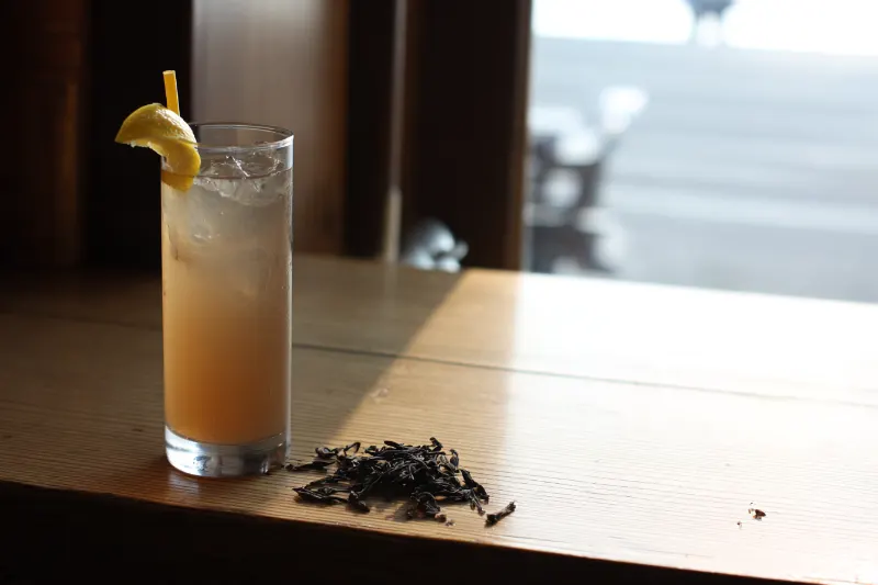 Tea Garden Collins: Chinese gin and cold oolong tea in a tall glass with lemon and tea leaves